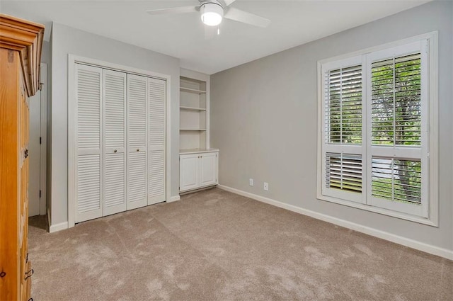 unfurnished bedroom with ceiling fan, a closet, light carpet, and multiple windows