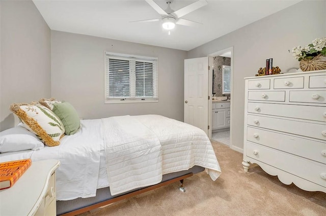 bedroom featuring light carpet, ensuite bathroom, and ceiling fan