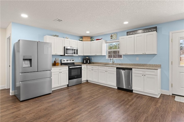 825 Red Hawk Dr, Waynesville, GA 31566 - kitchen featuring appliances with stainless steel finishes, a sink, white cabinets, dark wood-type flooring, and a textured ceiling