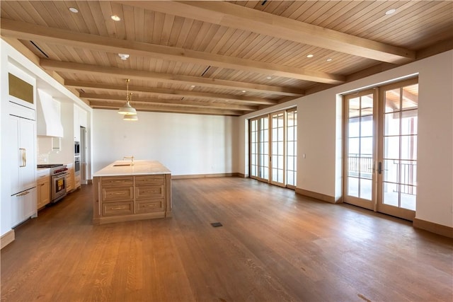 kitchen with high quality appliances, hanging light fixtures, hardwood / wood-style flooring, a kitchen island with sink, and french doors