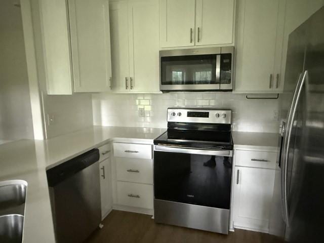 70 Harmonees Way, Ludowici, GA 31316 - kitchen with appliances with stainless steel finishes, light countertops, white cabinetry, tasteful backsplash, and dark wood-style floors