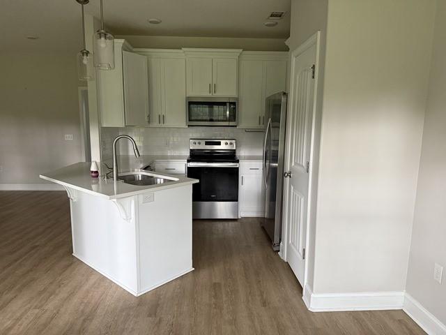 70 Harmonees Way, Ludowici, GA 31316 - kitchen featuring stainless steel appliances, a peninsula, dark wood finished floors, a breakfast bar, and decorative backsplash