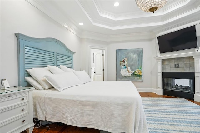 164 Sunrise Dr, Saint Simons Island, GA 31522 - bedroom featuring recessed lighting, a raised ceiling, dark wood-type flooring, crown molding, and a tiled fireplace