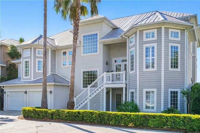 164 Sunrise Dr, Saint Simons Island, GA 31522 - view of front of home featuring metal roof, concrete driveway, an attached garage, stairway, and stucco siding