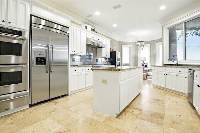 164 Sunrise Dr, Saint Simons Island, GA 31522 - kitchen with a warming drawer, a wealth of natural light, appliances with stainless steel finishes, and under cabinet range hood