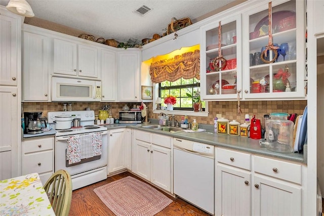 kitchen featuring white appliances, visible vents, a sink, white cabinetry, and decorative backsplash