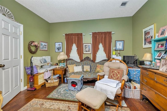 sitting room featuring a textured ceiling, visible vents, wood finished floors, and baseboards