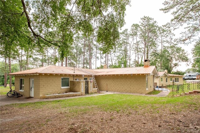 1002 Cherokee Cir, Waycross, GA 31501 - rear view of house with a chimney, metal roof, concrete block siding, and a yard