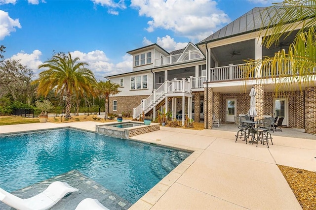 back of property with brick siding, a patio, a ceiling fan, a standing seam roof, and stairs