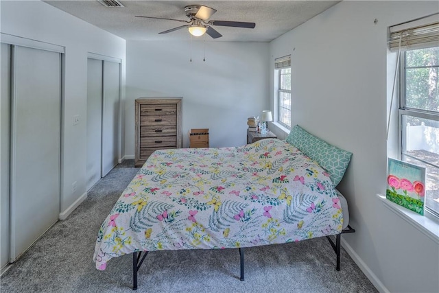 bedroom featuring carpet flooring, multiple windows, multiple closets, and ceiling fan