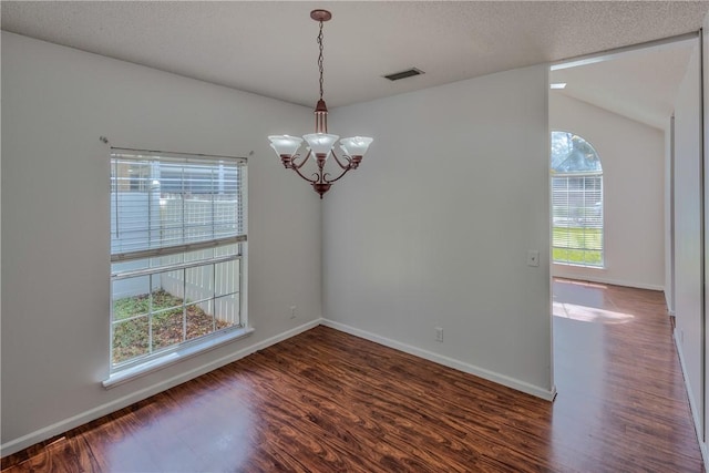 unfurnished room with a textured ceiling, dark hardwood / wood-style flooring, and a notable chandelier