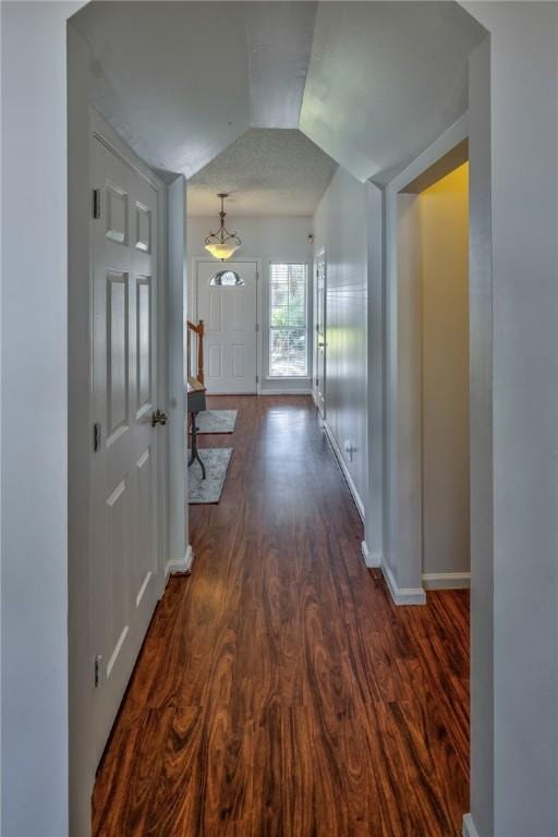 hallway with dark hardwood / wood-style floors and vaulted ceiling