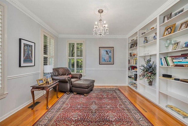 213 Five Pounds Rd, Saint Simons Island, GA 31522 - sitting room with wood finished floors, a chandelier, ornamental molding, built in shelves, and baseboards
