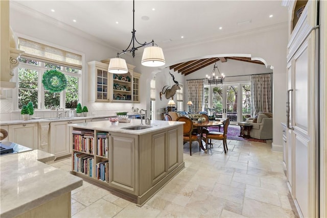 kitchen featuring arched walkways, stone tile floors, glass insert cabinets, ornamental molding, and open floor plan