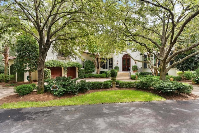 view of front of home with driveway, stucco siding, a garage, and french doors