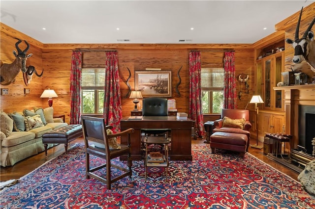 office with a fireplace, wood finished floors, visible vents, and wooden walls