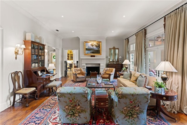 living room with ornamental molding, a fireplace, baseboards, and wood finished floors