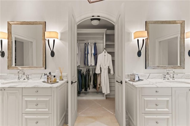 bathroom with a spacious closet, two vanities, and a sink