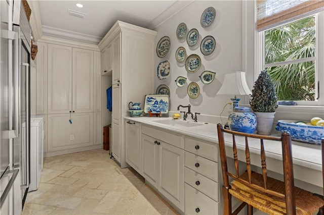 interior space featuring stone tile flooring, light countertops, visible vents, ornamental molding, and a sink