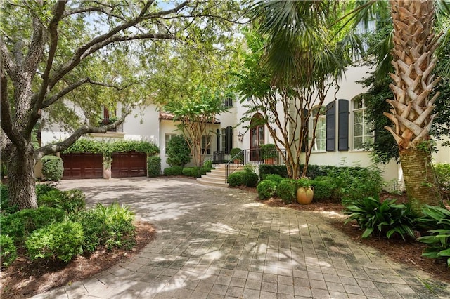 view of front facade featuring a garage, decorative driveway, and stucco siding