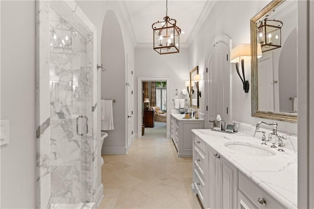 bathroom with a marble finish shower, baseboards, a sink, crown molding, and two vanities