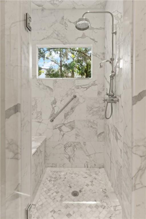 bathroom featuring a healthy amount of sunlight and a marble finish shower