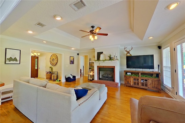 living area with light wood-style floors, a raised ceiling, a wealth of natural light, and visible vents