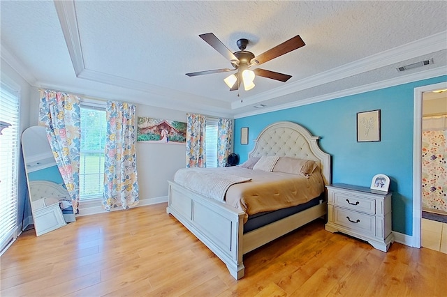 bedroom with light wood-style floors, a textured ceiling, baseboards, visible vents, and ornamental molding