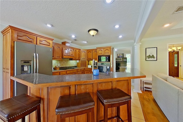 kitchen with crown molding, oven, dark countertops, a kitchen breakfast bar, and built in microwave