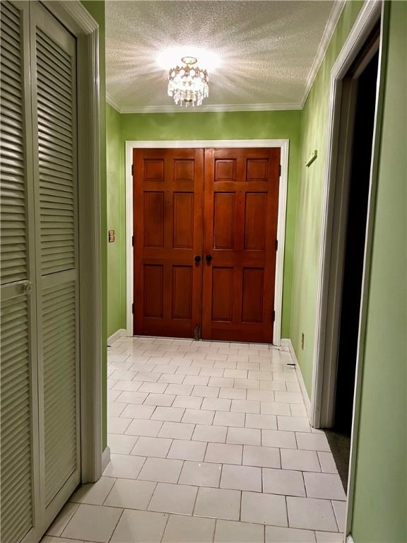 interior space featuring crown molding, light tile patterned floors, a textured ceiling, and a notable chandelier