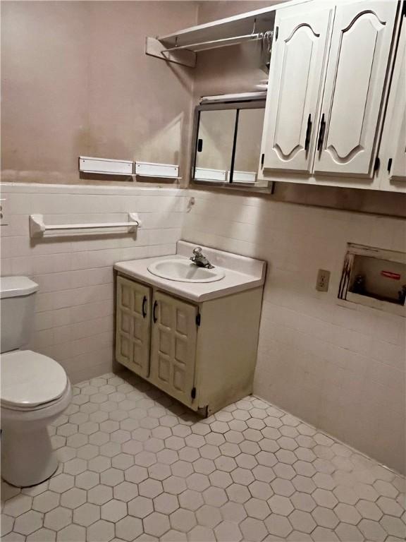 bathroom with vanity, tile walls, and toilet