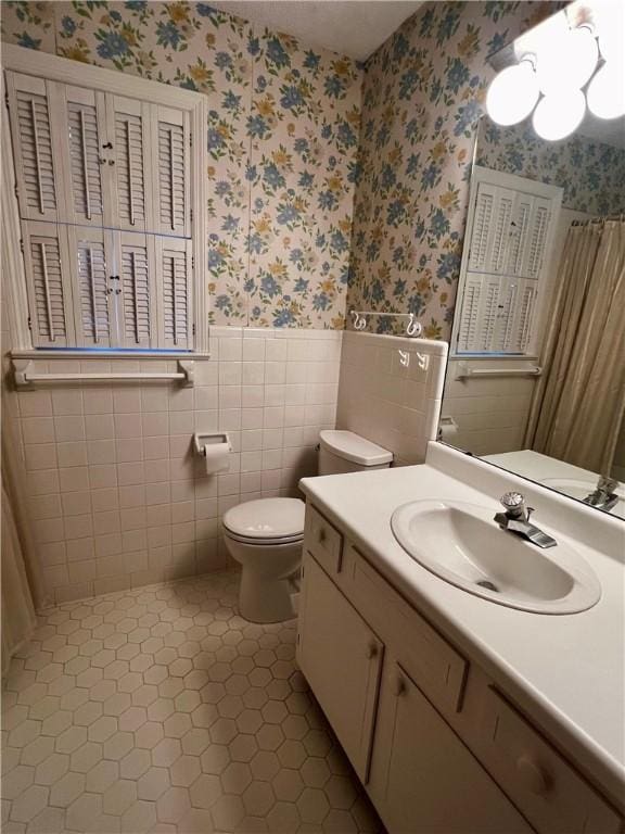 bathroom featuring tile patterned flooring, vanity, toilet, and tile walls