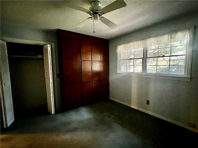 unfurnished bedroom featuring ceiling fan, a closet, and dark colored carpet