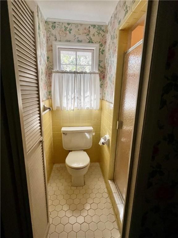 bathroom with tile patterned floors, toilet, and a shower with shower door