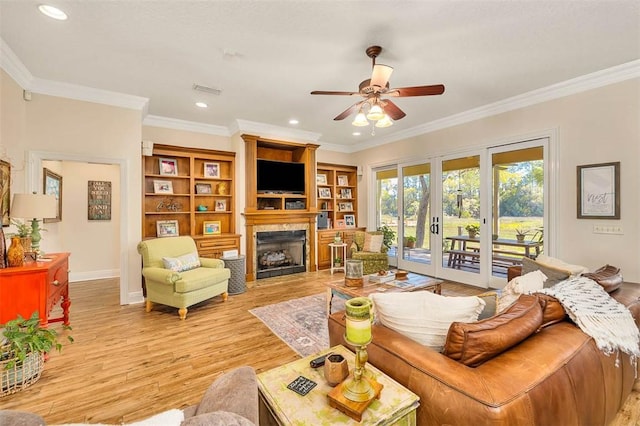 living room with french doors, light hardwood / wood-style flooring, ceiling fan, and crown molding