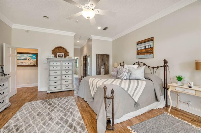 bedroom with light wood-type flooring, ornamental molding, a textured ceiling, ceiling fan, and connected bathroom