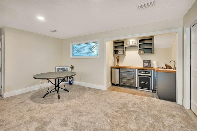 bar with butcher block countertops, sink, and light carpet