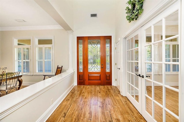 entrance foyer featuring light hardwood / wood-style floors, ornate columns, and crown molding