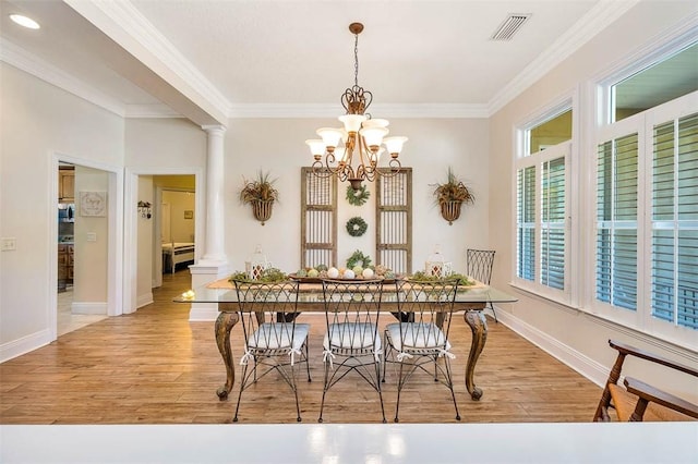 dining space with light wood-type flooring, ornate columns, crown molding, and a chandelier