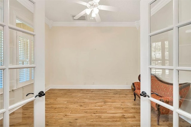 empty room with ornamental molding, light hardwood / wood-style flooring, and french doors