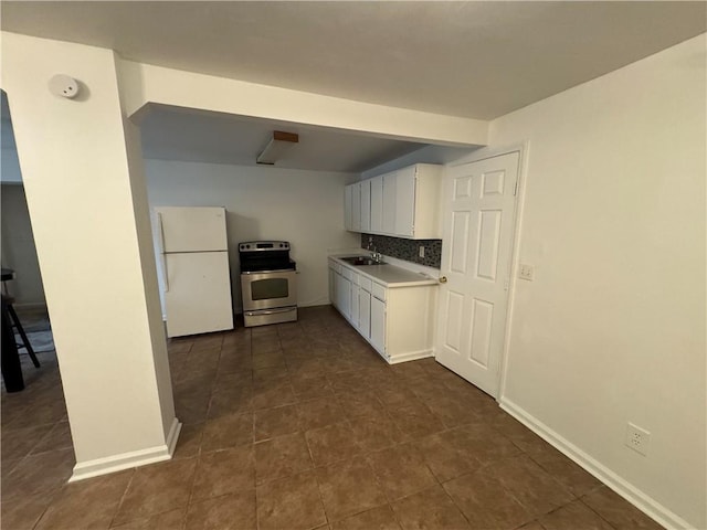 kitchen featuring white refrigerator, sink, white cabinets, backsplash, and stainless steel range with electric stovetop