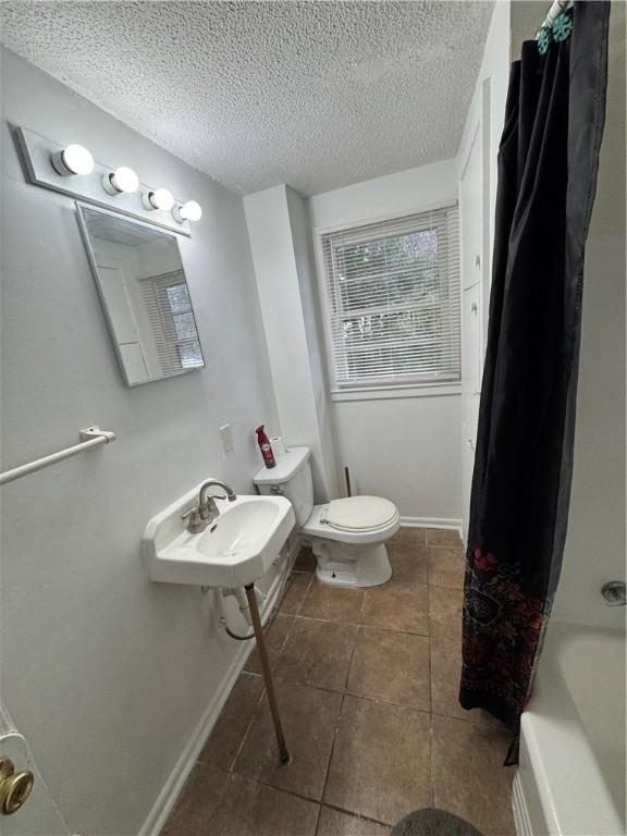 full bathroom featuring sink, shower / tub combo, a textured ceiling, and toilet