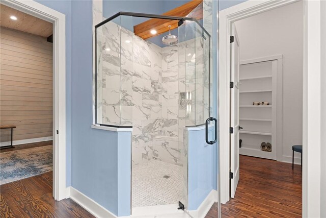 bathroom featuring wooden walls, wood-type flooring, and an enclosed shower