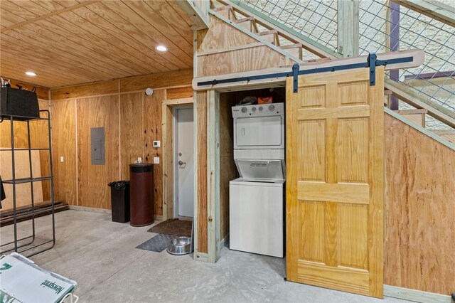 interior space featuring electric panel, wood ceiling, stacked washer and dryer, and wooden walls