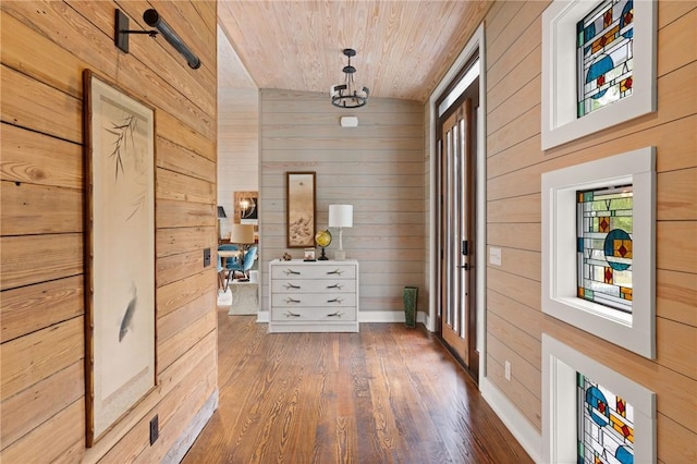 corridor with wood walls, lofted ceiling, dark wood-type flooring, and wooden ceiling