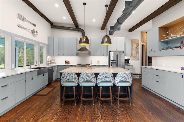 kitchen with a kitchen breakfast bar, hanging light fixtures, an island with sink, beam ceiling, and stainless steel appliances