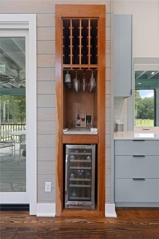 bar featuring dark hardwood / wood-style floors, gray cabinets, and beverage cooler