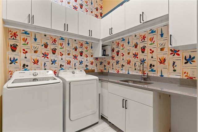 laundry area featuring light tile patterned floors, washer and clothes dryer, and sink