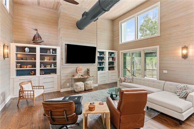 living room with wooden walls, wood-type flooring, and high vaulted ceiling