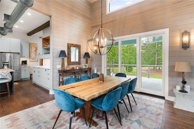 dining area featuring wooden walls, dark wood-type flooring, and a notable chandelier